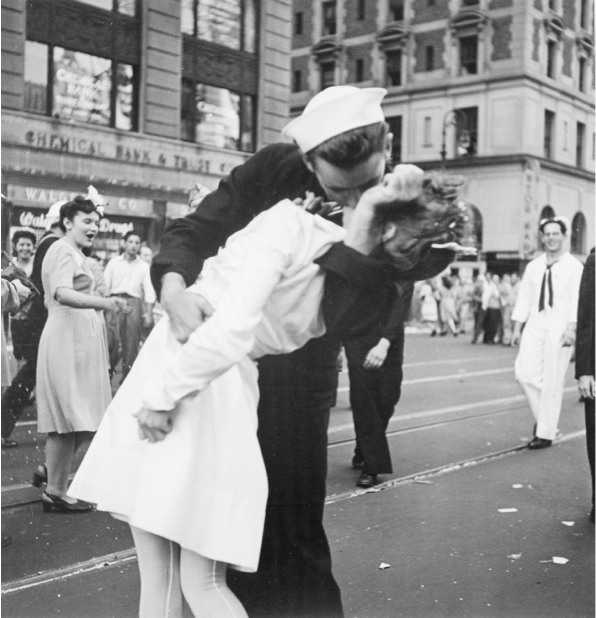 A sailor and nurse kissing on a city street.